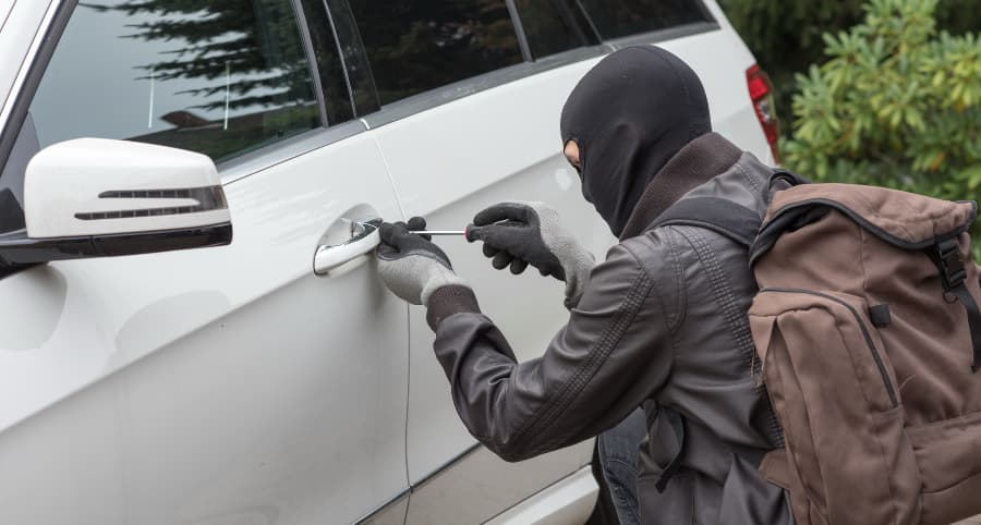Thief trying to break into a white car in a residential area